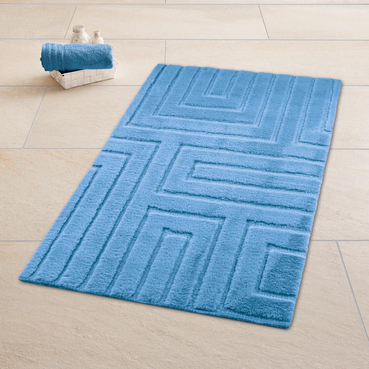 Blauer Badteppich mit Muster auf Fliesenboden, daneben Korb mit Handtuch.