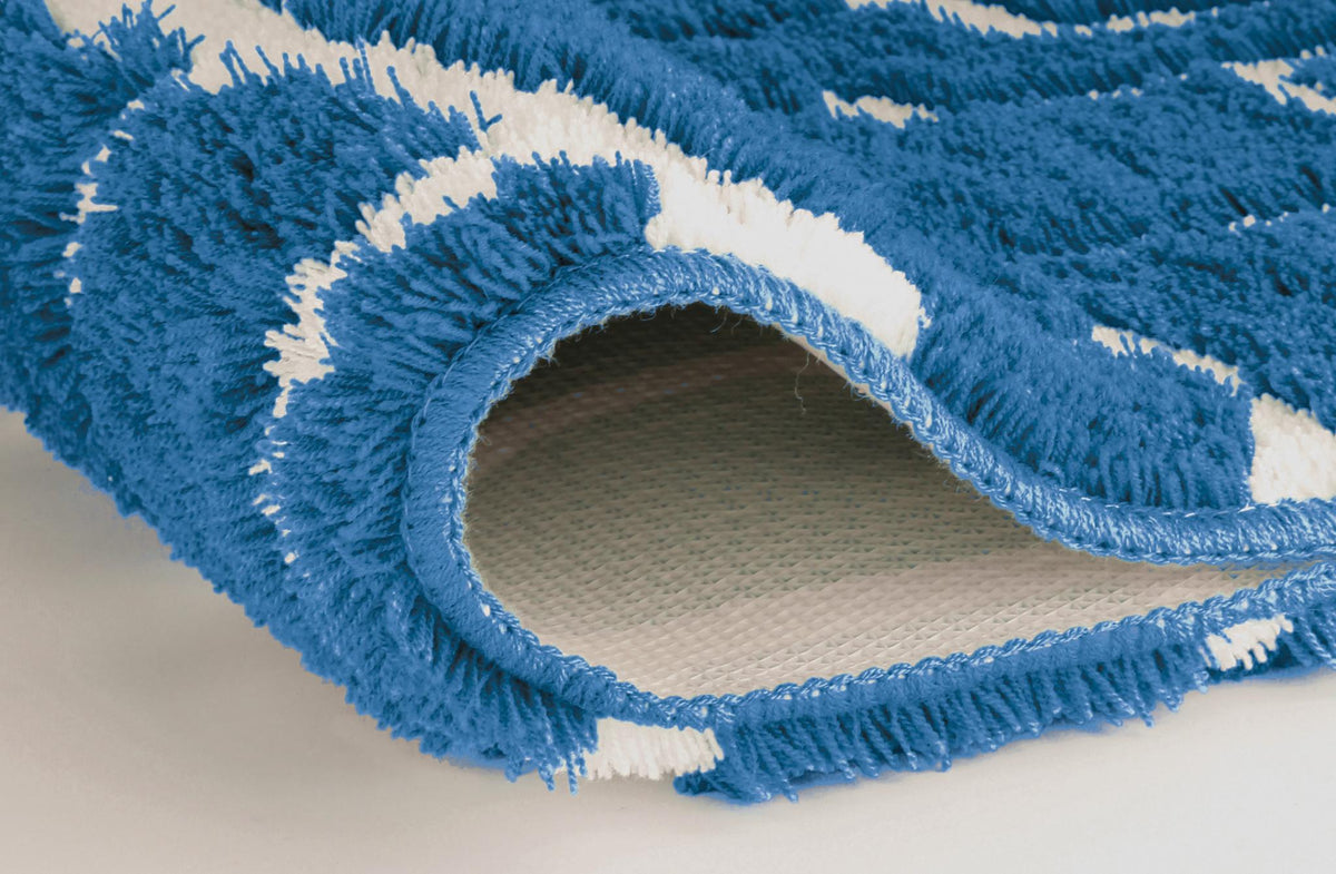 Nahaufnahme eines blau-weißen Badteppichs mit hochgeklappter Ecke.