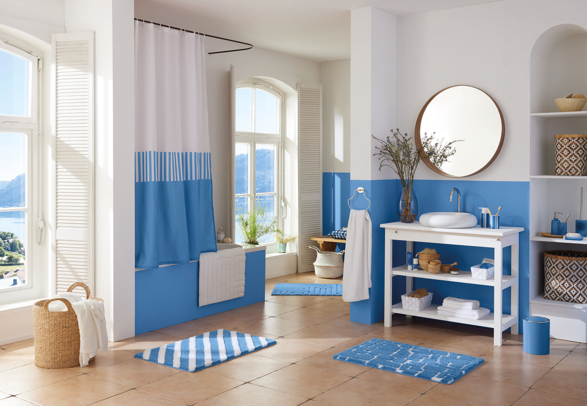 Helles Bad mit blauen Badteppichen, Waschplatz und Duschvorhang.