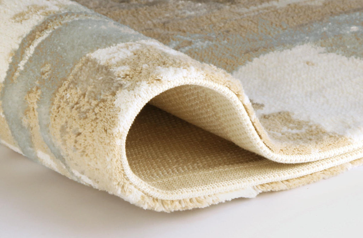 Zusammengerollter cremefarbener Hochflorteppich mit weicher Struktur.