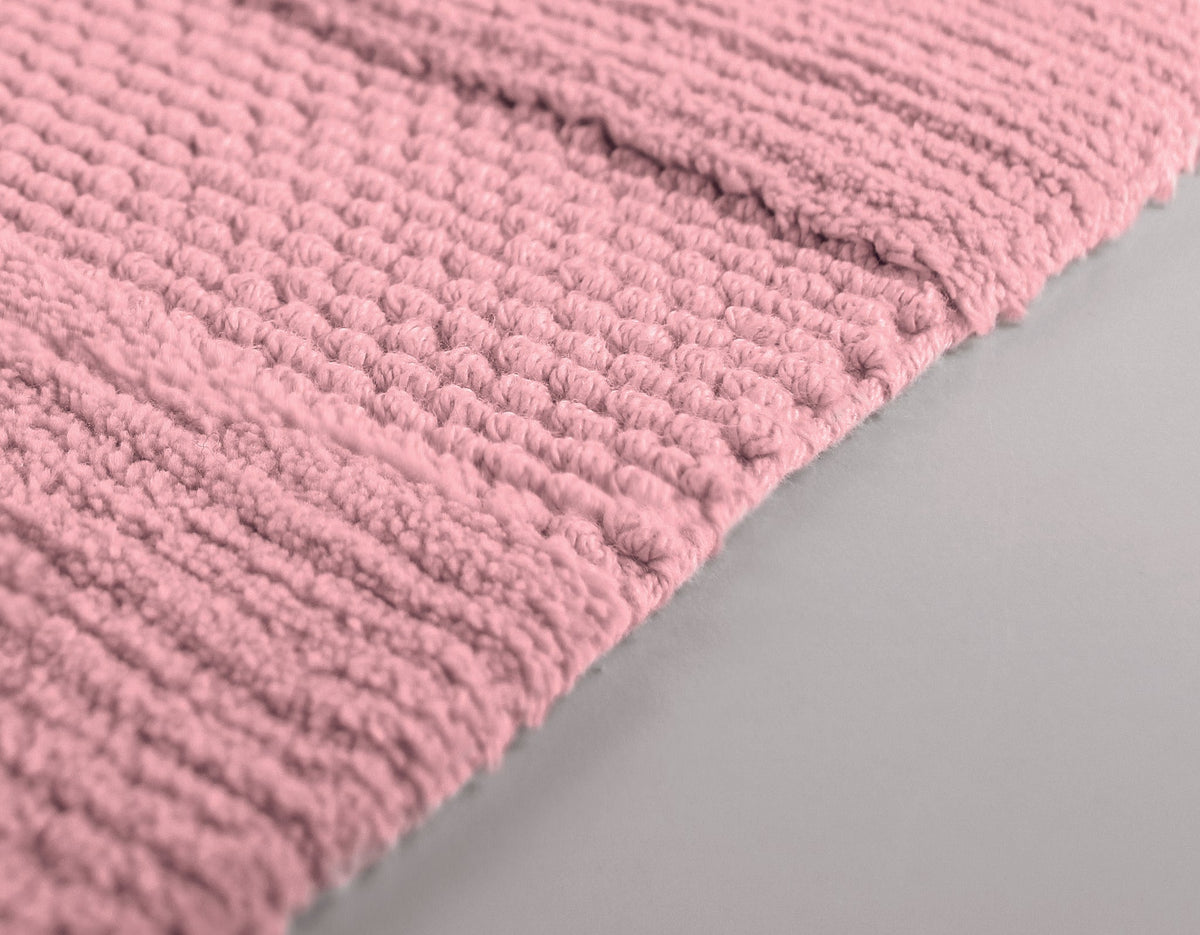 Nahaufnahme einer rosa, dick strukturierten Badematte auf hellem Boden
