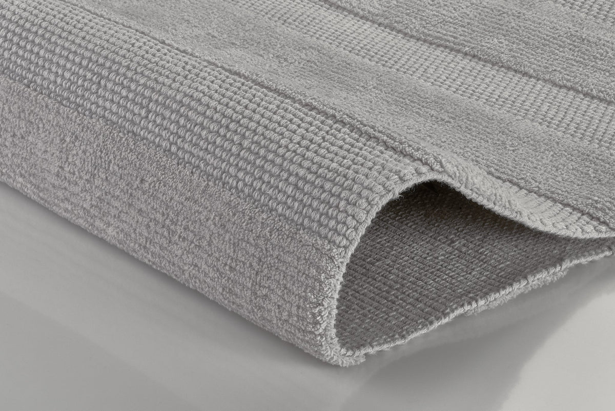 Gefaltetes hellgraues Handtuch in Nahaufnahme auf glatter Fläche