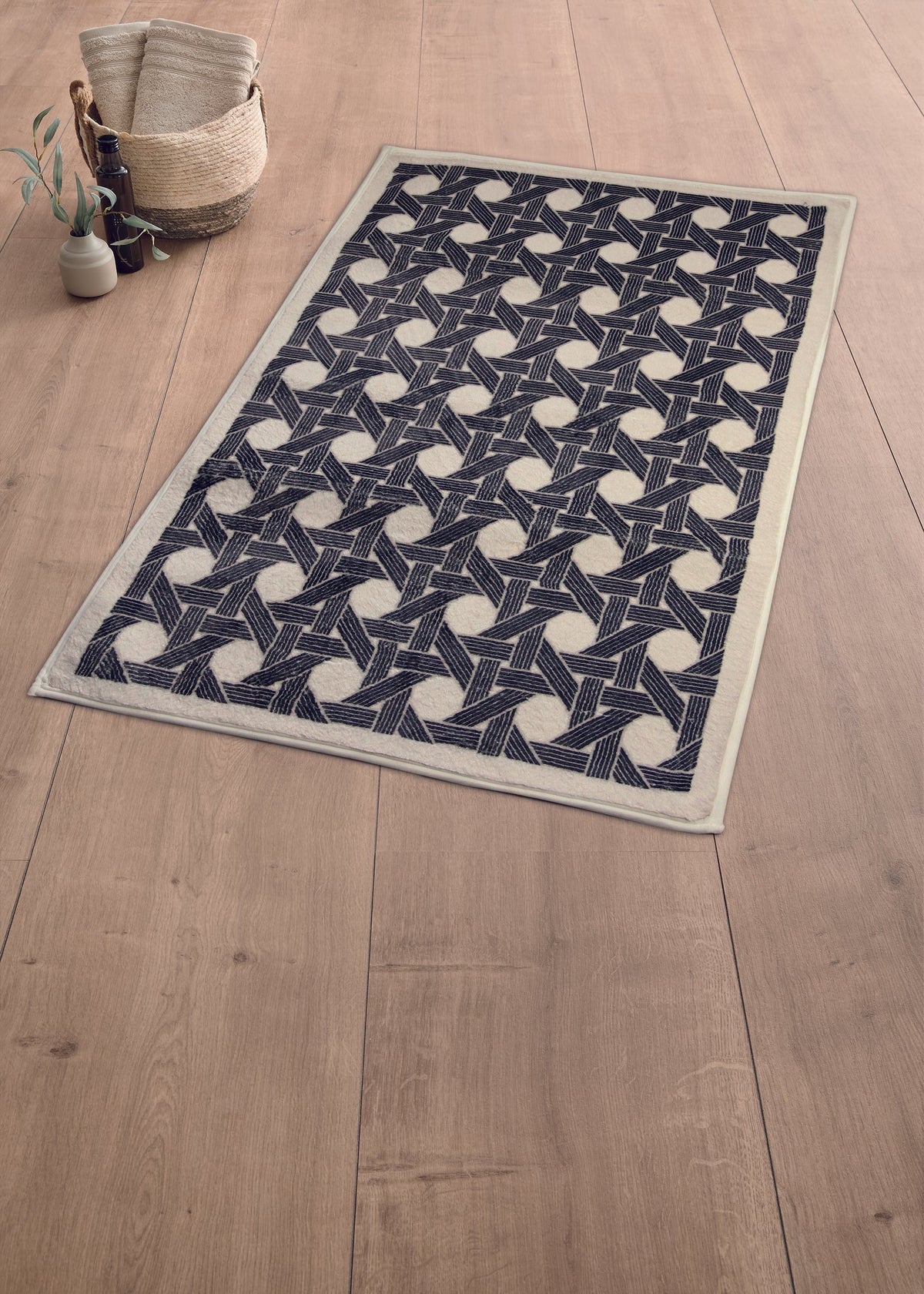 Schwarze Badematte mit geometrischem Muster auf großem hellem Holzboden