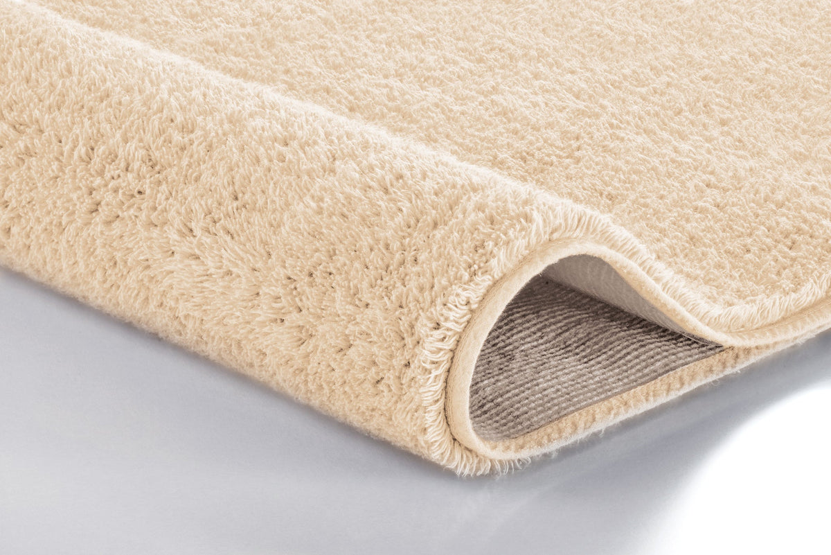 Beiger, flauschiger Badteppich in Nahaufnahme mit umgeschlagener Ecke