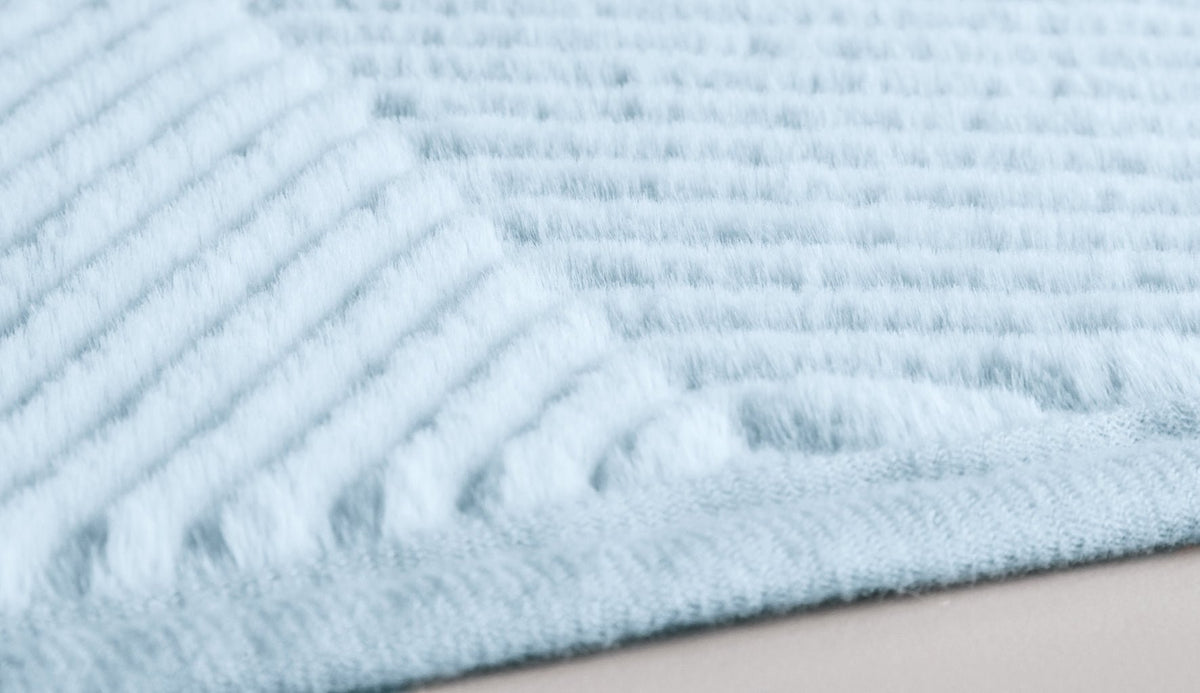 Hellblaue, flauschige Badematte mit feiner Rippstruktur in Nahaufnahme