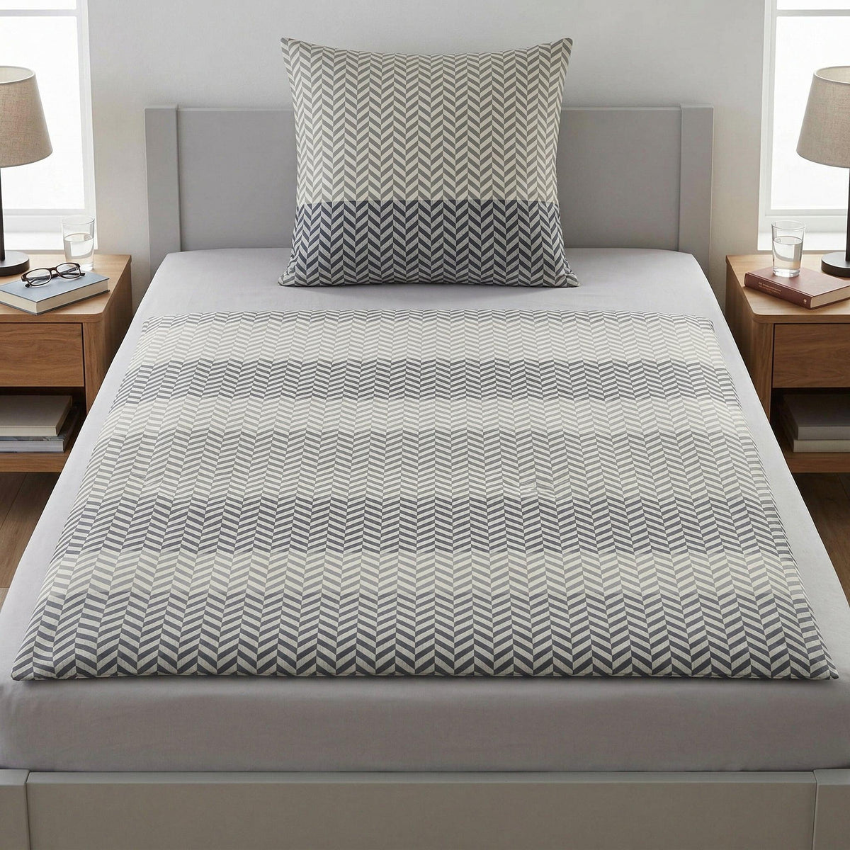 Graue Bettwäsche mit geometrischem Muster auf modernem Bett.
