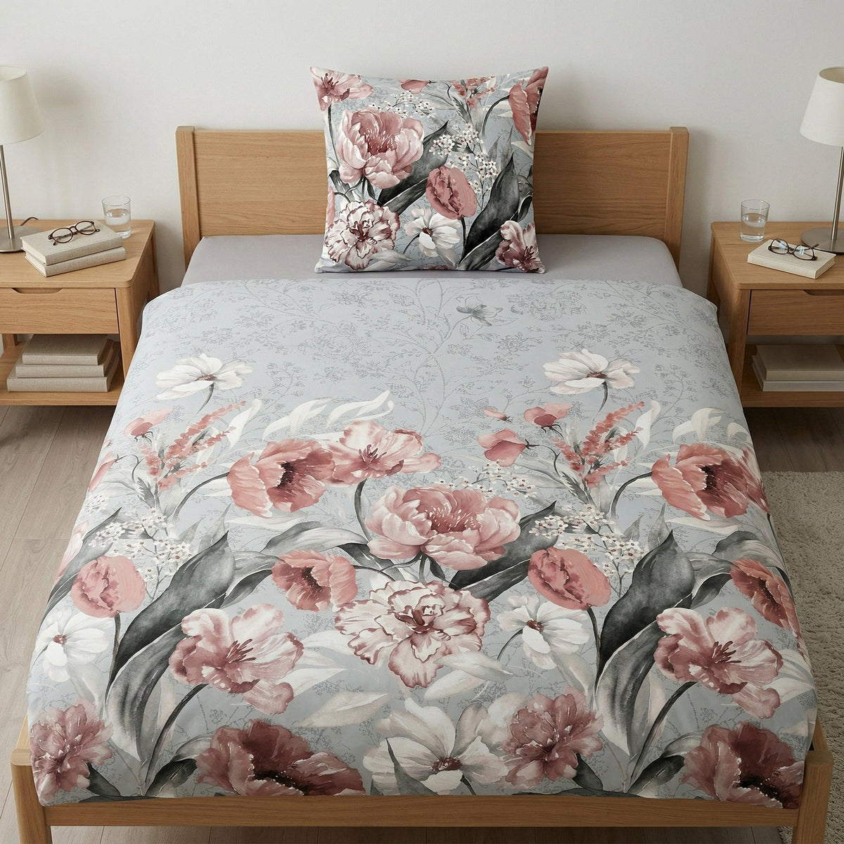 Blumige Bettwäsche in Rosa und Grau auf einem Holzbett.