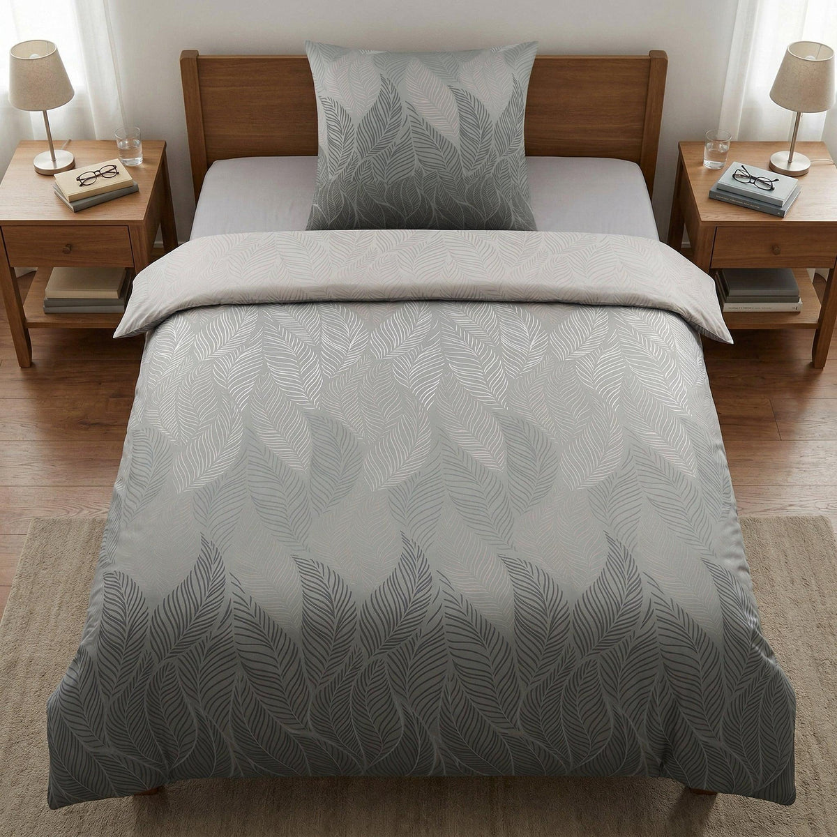 Graue Bettwäsche mit Blattmuster auf Holzbett im hellen Schlafzimmer.