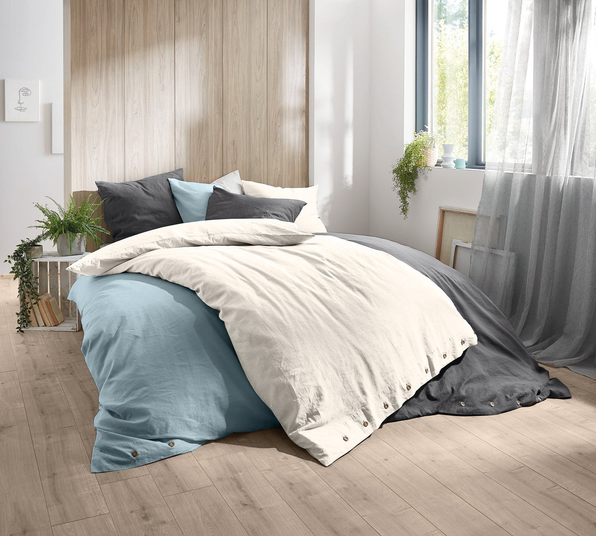 Modernes Doppelbett mit mehrfarbiger Bettwäsche in hellem Schlafzimmer