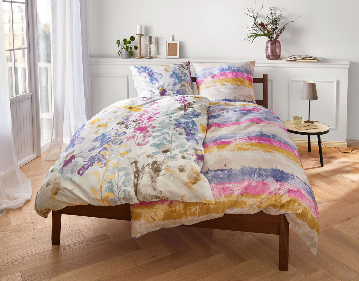 Holzbett mit bunter Bettwäsche in hellem Schlafzimmer mit Dekoration