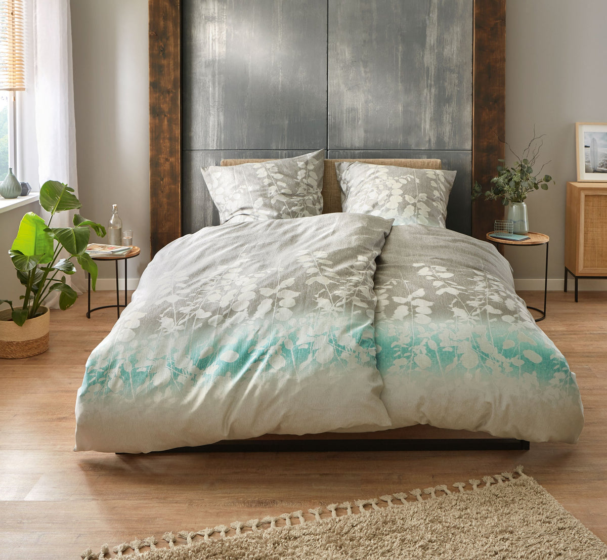 Doppelbett mit grauer Bettwäsche und floralen Mustern im Schlafzimmer