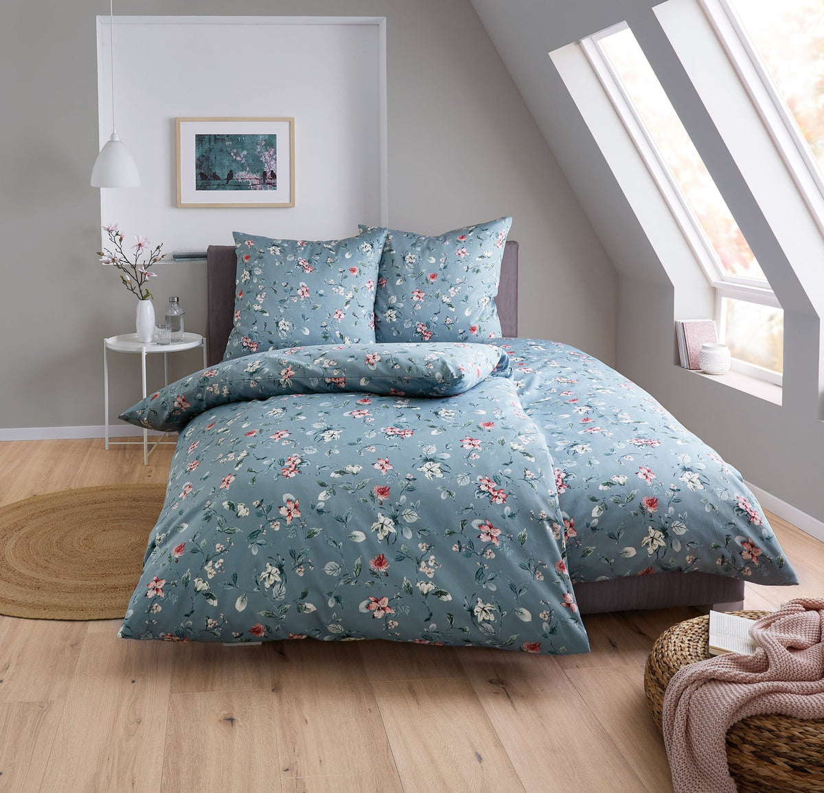 Doppelbett mit blauer, geblümter Bettwäsche in hellem Schlafzimmer