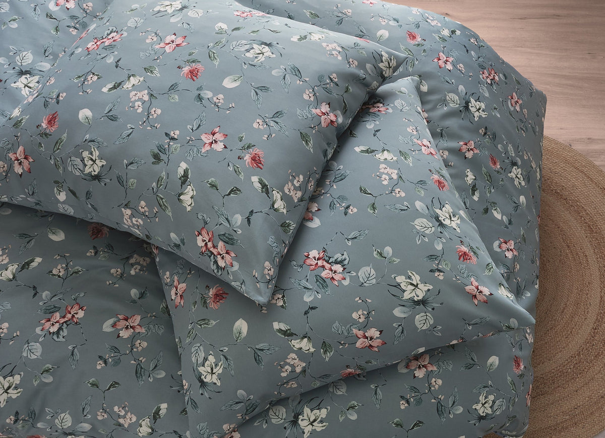 Blaue Bettwäsche mit zartem Blumenmuster auf rundem Juteteppich