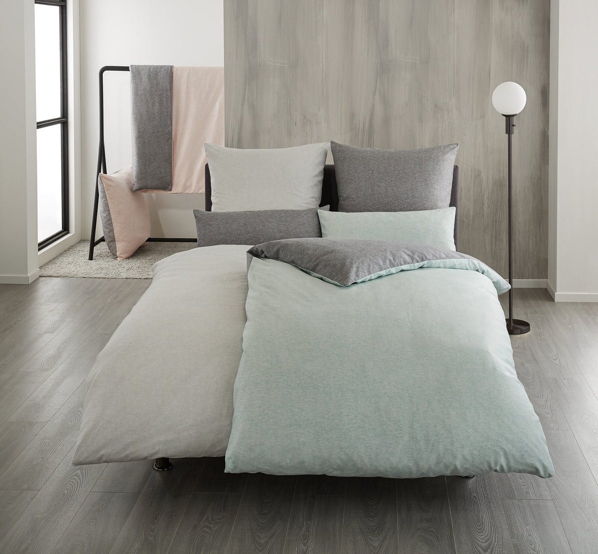 Modernes Doppelbett mit grau-mintfarbener Bettwäsche in heller Raum