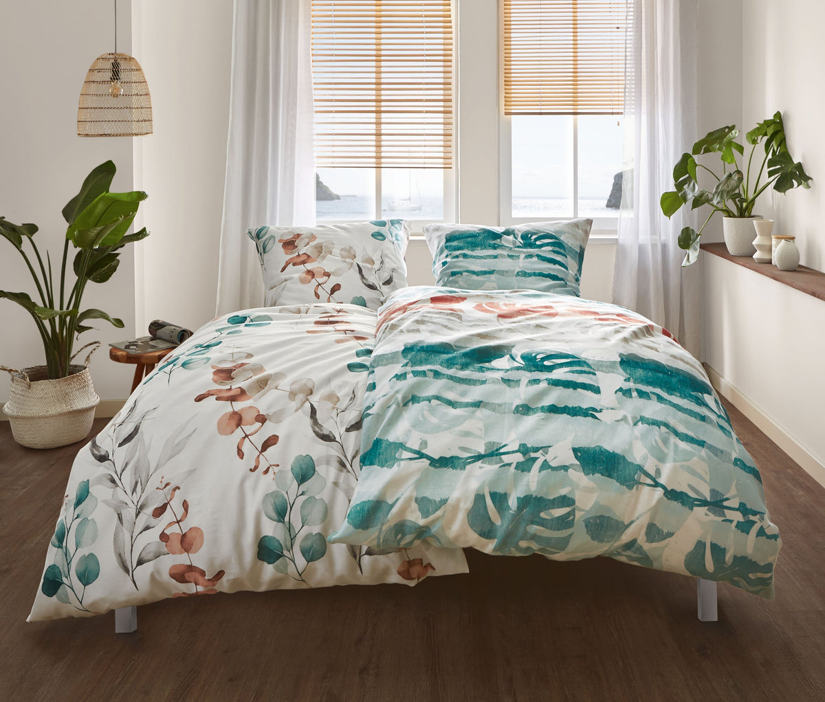Doppelbett mit bunter Bettwäsche im Pflanzenmuster und Zimmerpflanzen