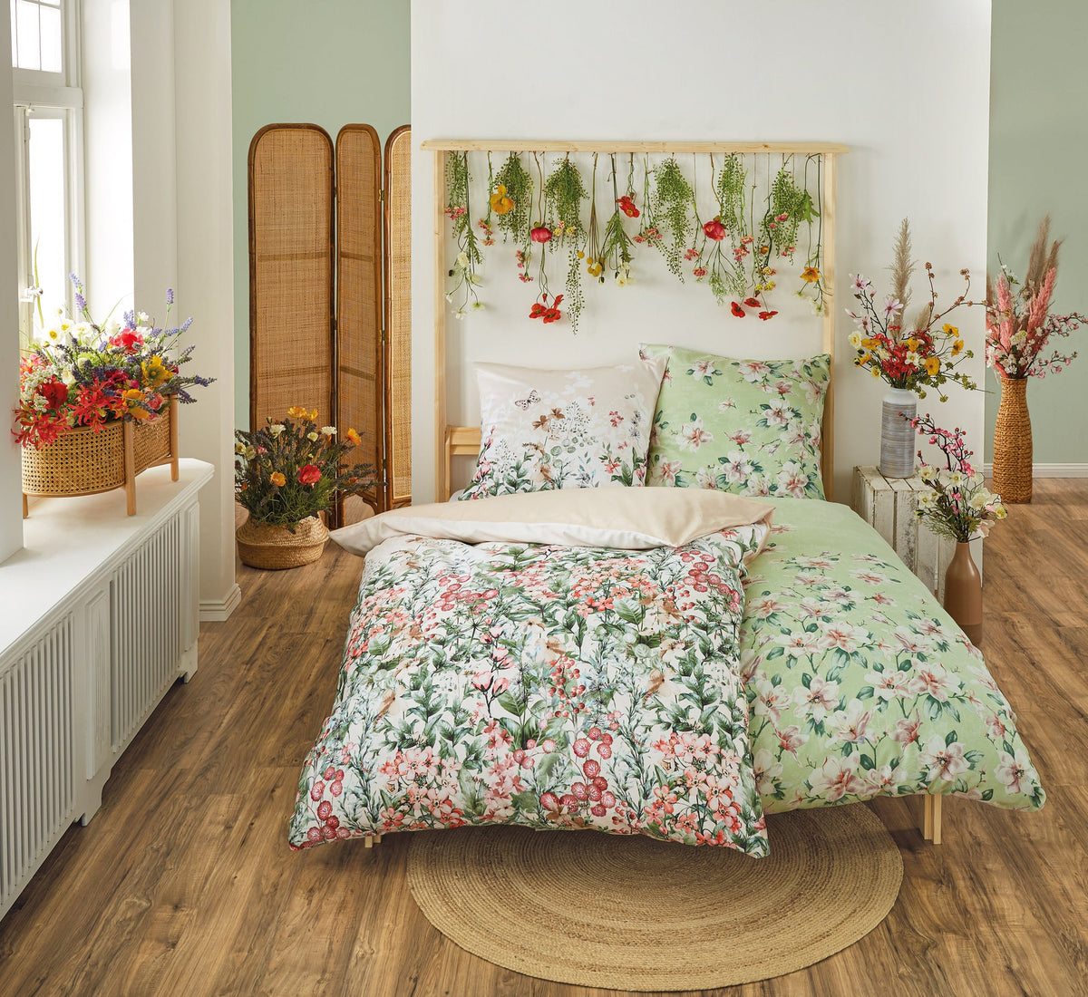 Helles Schlafzimmer mit Blumenbettwäsche und hängenden Pflanzen