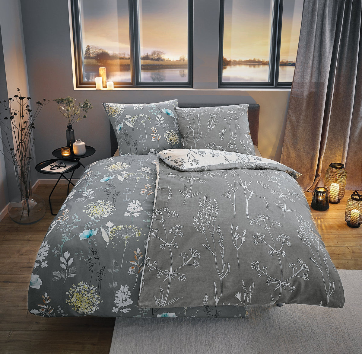 Graue Bettwäsche mit Blumenmuster in gemütlich beleuchtetem Schlafzimmer