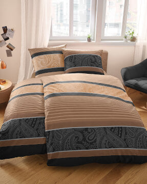Modernes Bett mit gemusterter Bettwäsche vor hellem Fenster im Schlafzimmer.