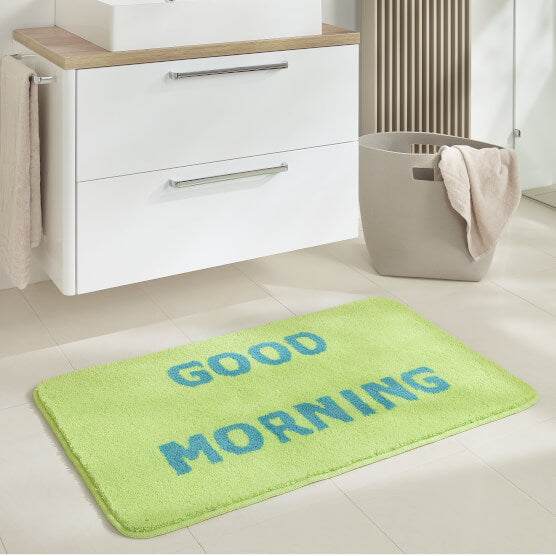 Grüne Badematte mit blauem Schriftzug „Good Morning“ im hellen Bad.