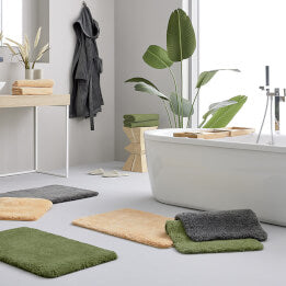Modernes Bad mit freistehender Wanne und farbigen Badematten.