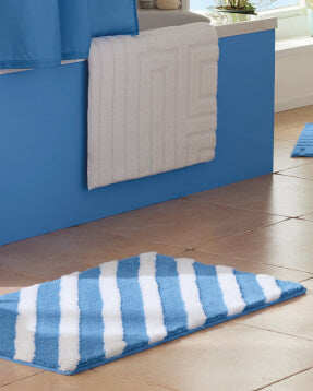 Blau-weißer Badteppich vor Badewanne mit weißem Vorleger.