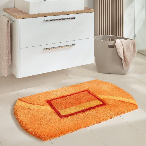 Orange Badematte vor weißem Waschbeckenunterschrank im modernen Bad