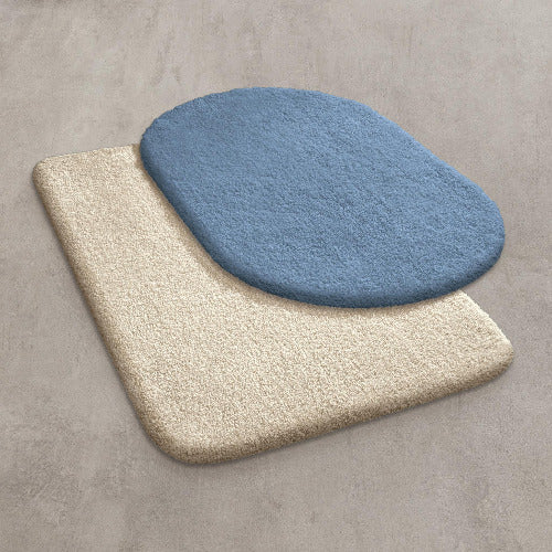 Zwei überlappende Badteppiche in Beige und Blau liegen auf Betonboden