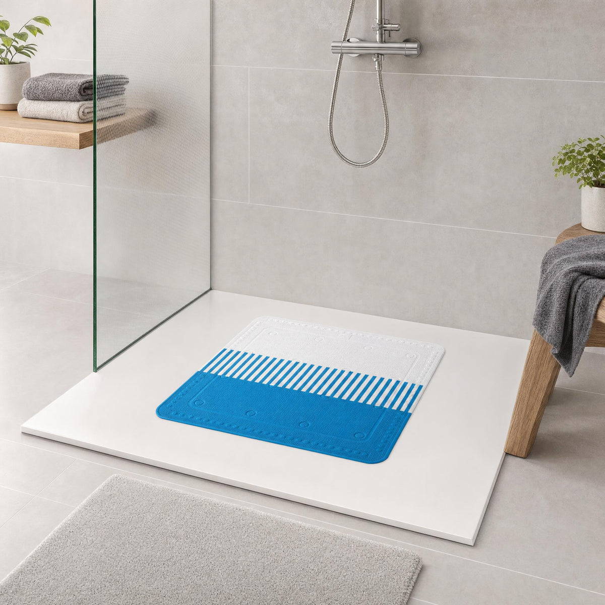 Blaue Duschmatte auf weißer Duschfläche in modernem Badezimmer.
