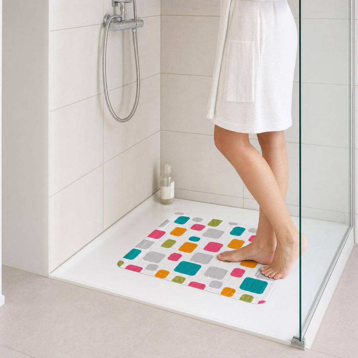 Person steht im Handtuch auf bunter  Antirutschmatte in moderner Dusche.
