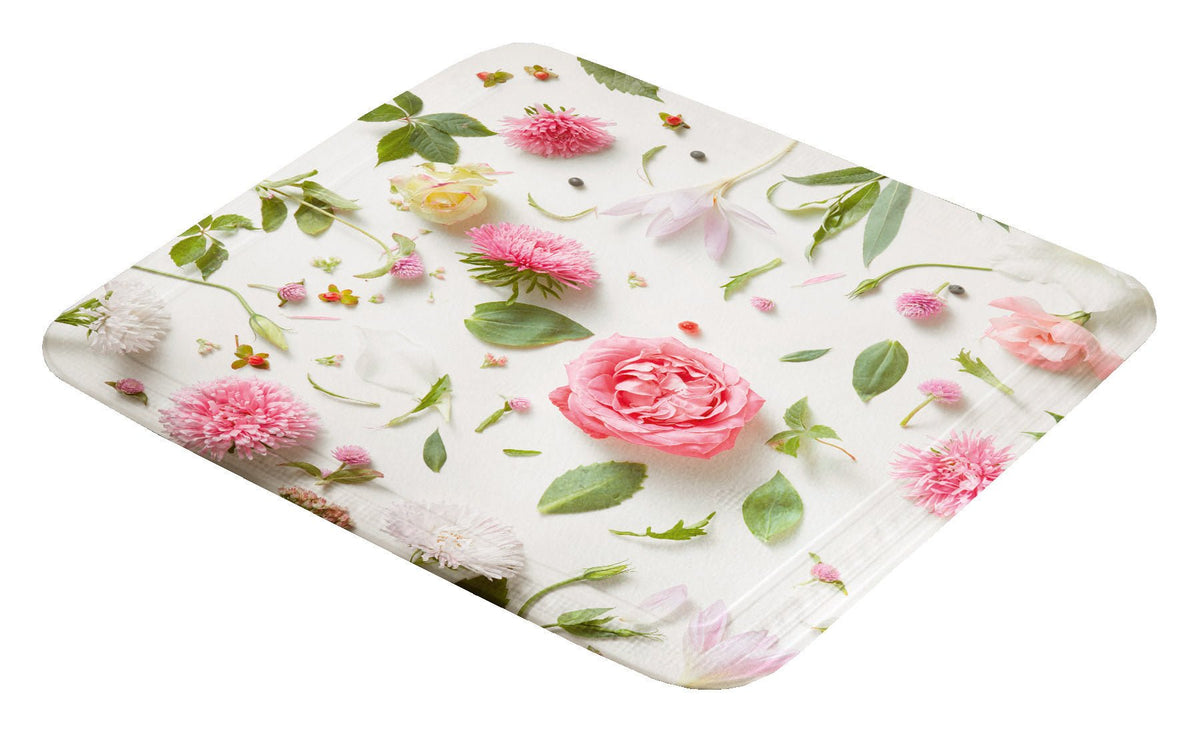 Weiße Badematte mit rosa und grünen Blumenmotiven von oben fotografiert