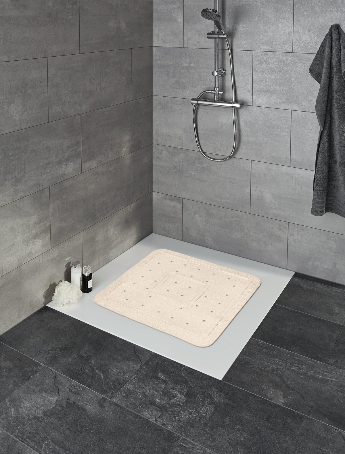 Rutschfeste beige Badematte in gefliester Dusche mit Duschkopf an Wand