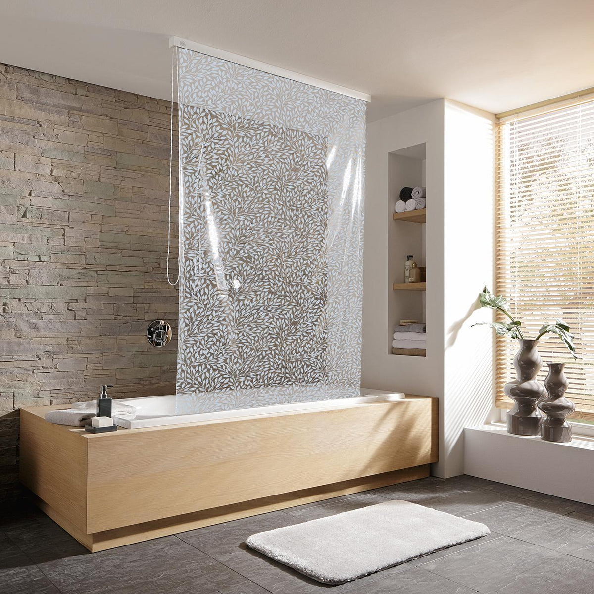 Modernes Bad mit Badewanne und perlgrauem Duschrollo vor Steinwand.