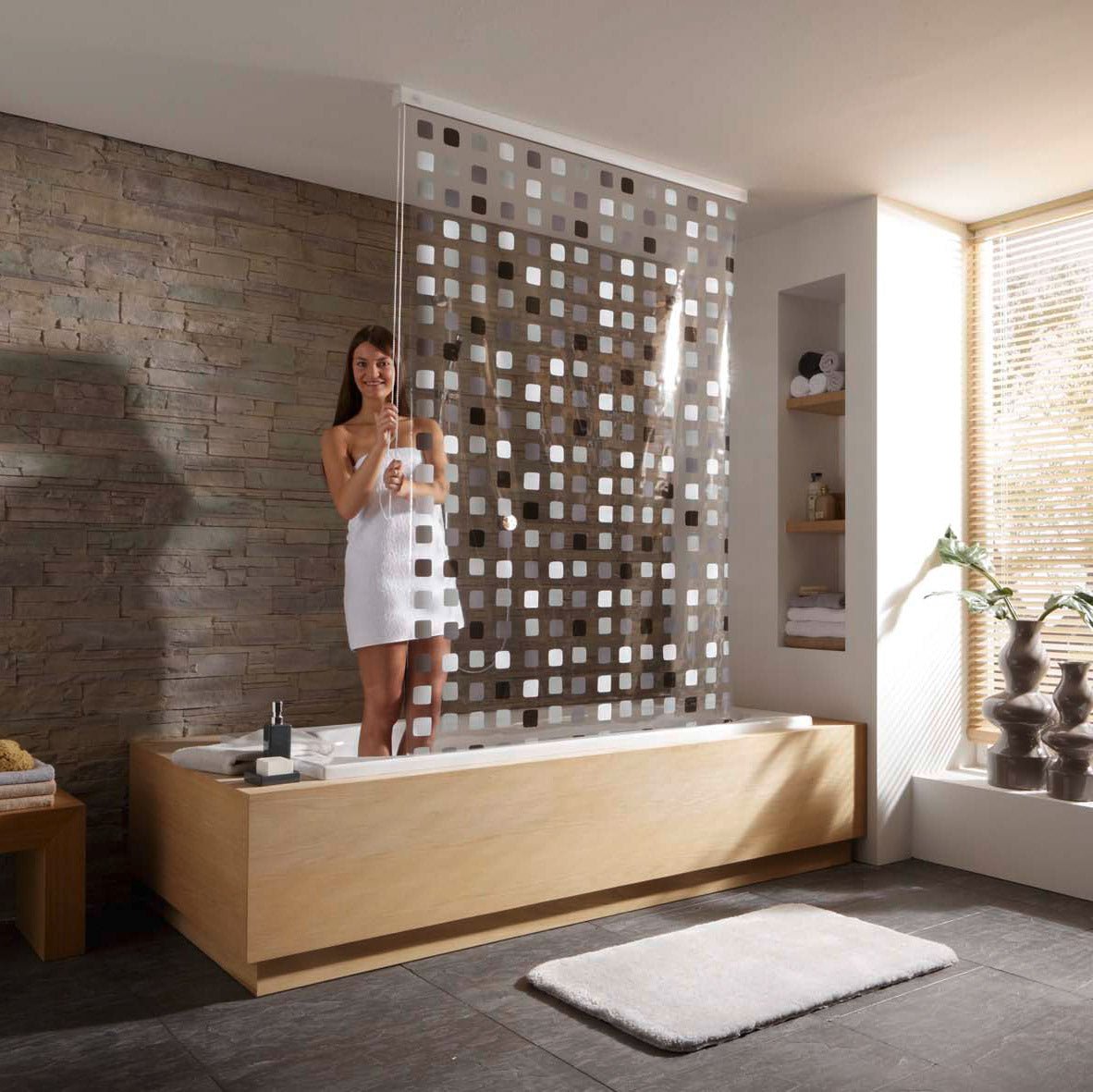 Frau in Badewanne hinter modernem Duschvorhang in hellem Designbad
