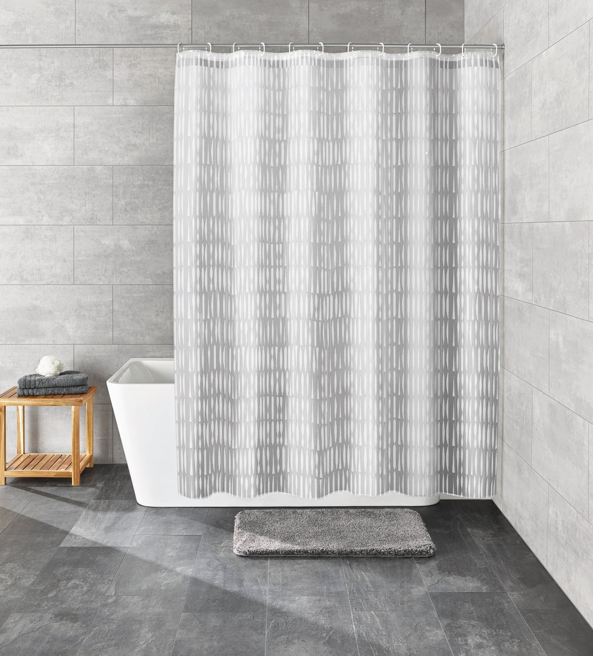 Grauer Duschvorhang vor Badewanne in modern gefliestem Badezimmer
