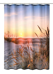 Sonnenuntergang über Sanddünen mit Gräsern am ruhigen Strand und Meer