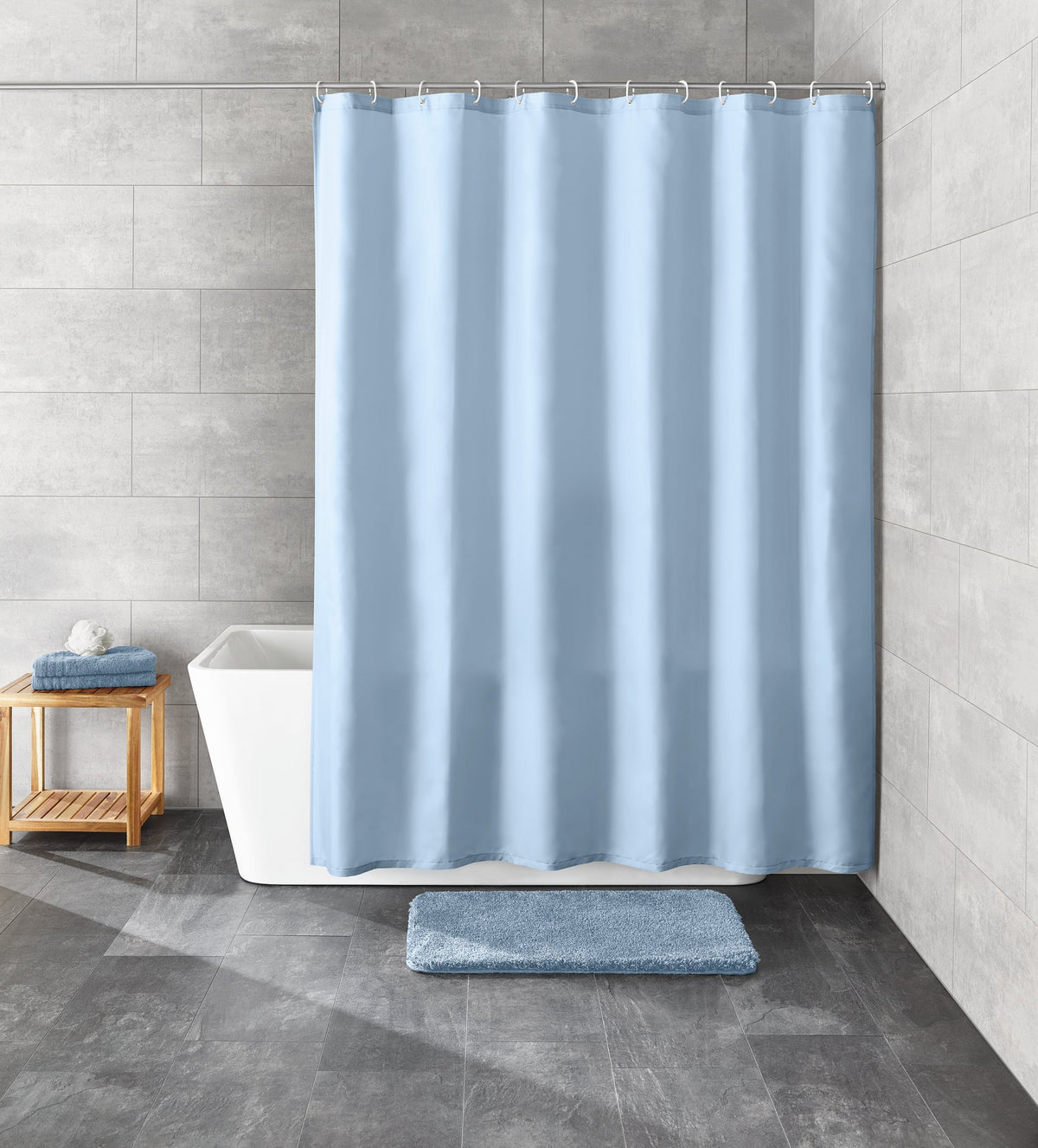 Großer hellblauer Duschvorhang vor Badewanne mit flauschiger Badematte