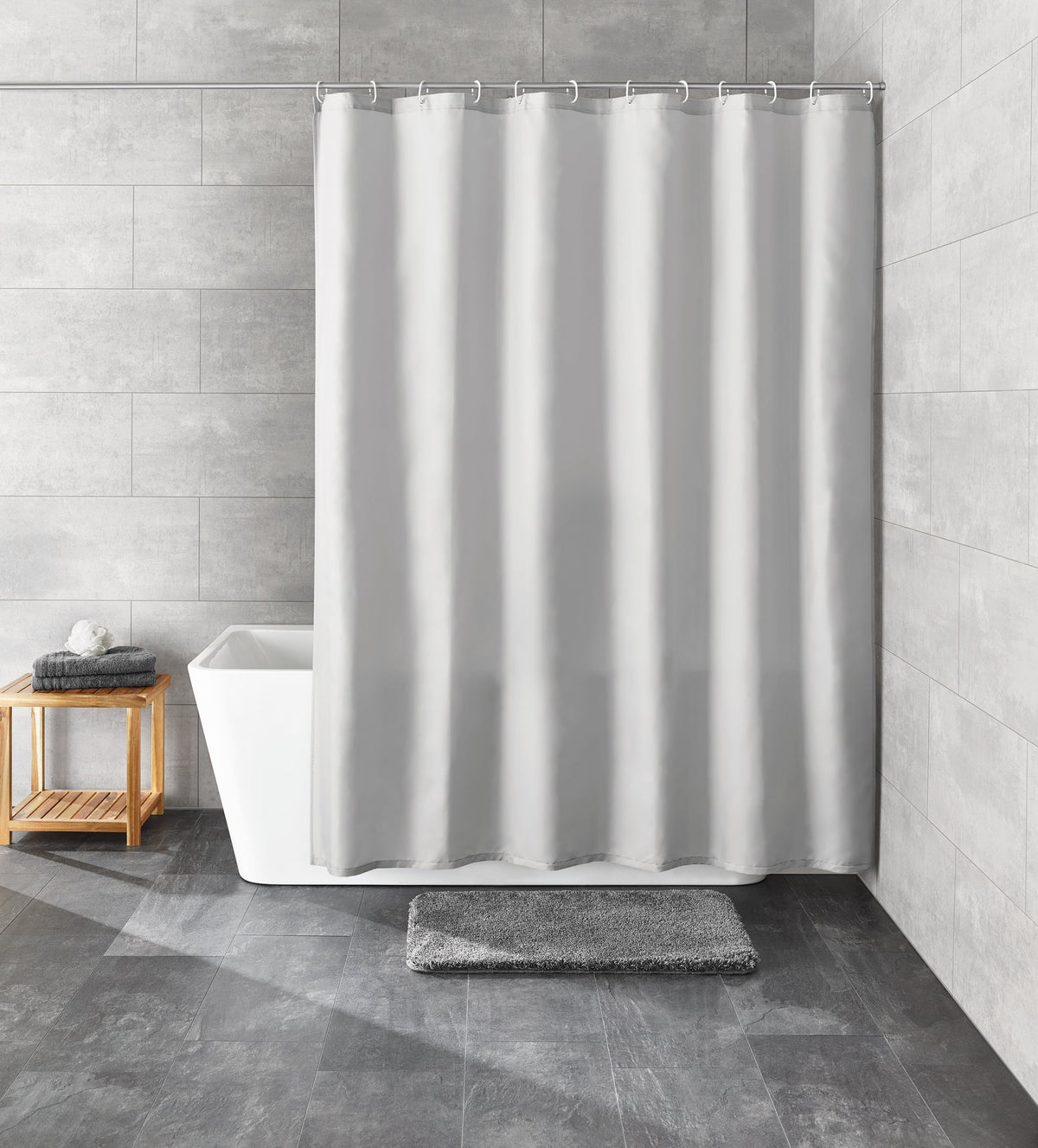 Grauer Duschvorhang vor Badewanne mit Badematte in modernem Designbad
