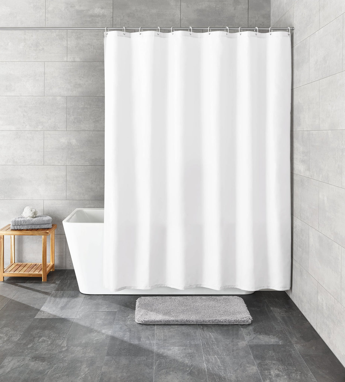 Weißer Duschvorhang in grauem Bad mit Wanne, Badematte und Hocker aus Holz