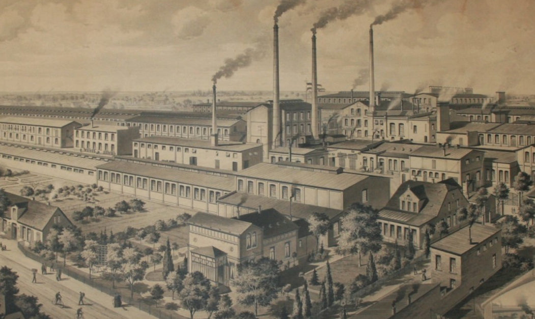 Historische Fabrikanlage mit Schornsteinen, Rauch und Gehwegen vorn