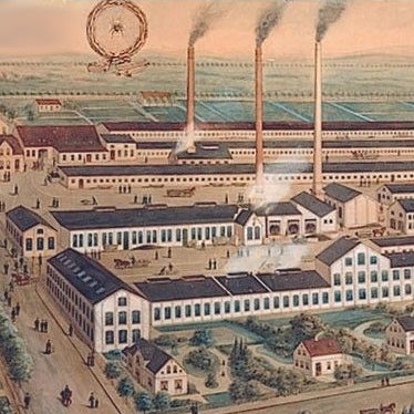 Historische Fabrikanlage mit mehreren Schornsteinen in ländlicher Umgebung