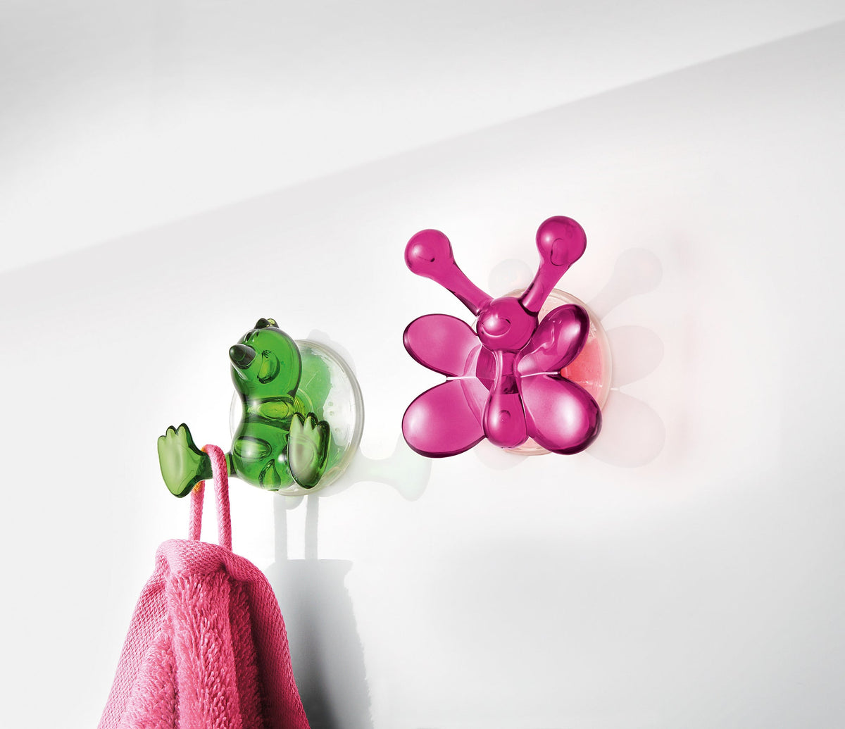 Bunte Wandhaken in Frosch- und Schmetterlingsform mit rosa Handtuch