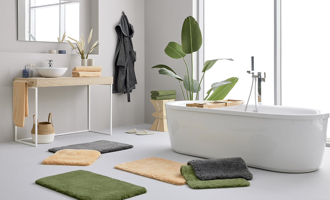Modernes Bad mit freistehender Wanne, Pflanzen und bunten Badematten