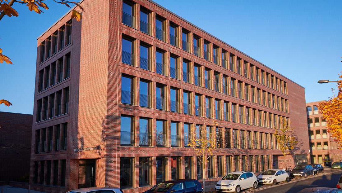 Modernes Backsteingebäude mit parkenden Autos an sonniger Straße