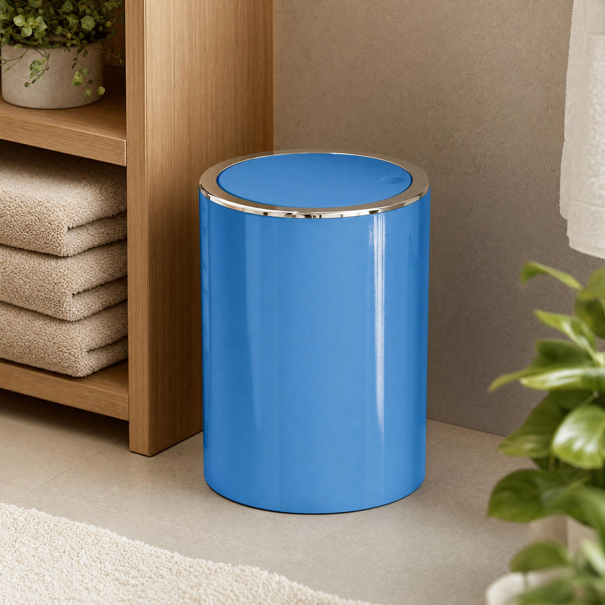 Blauer Badezimmereimer neben Holzregal mit Handtüchern und Pflanze.