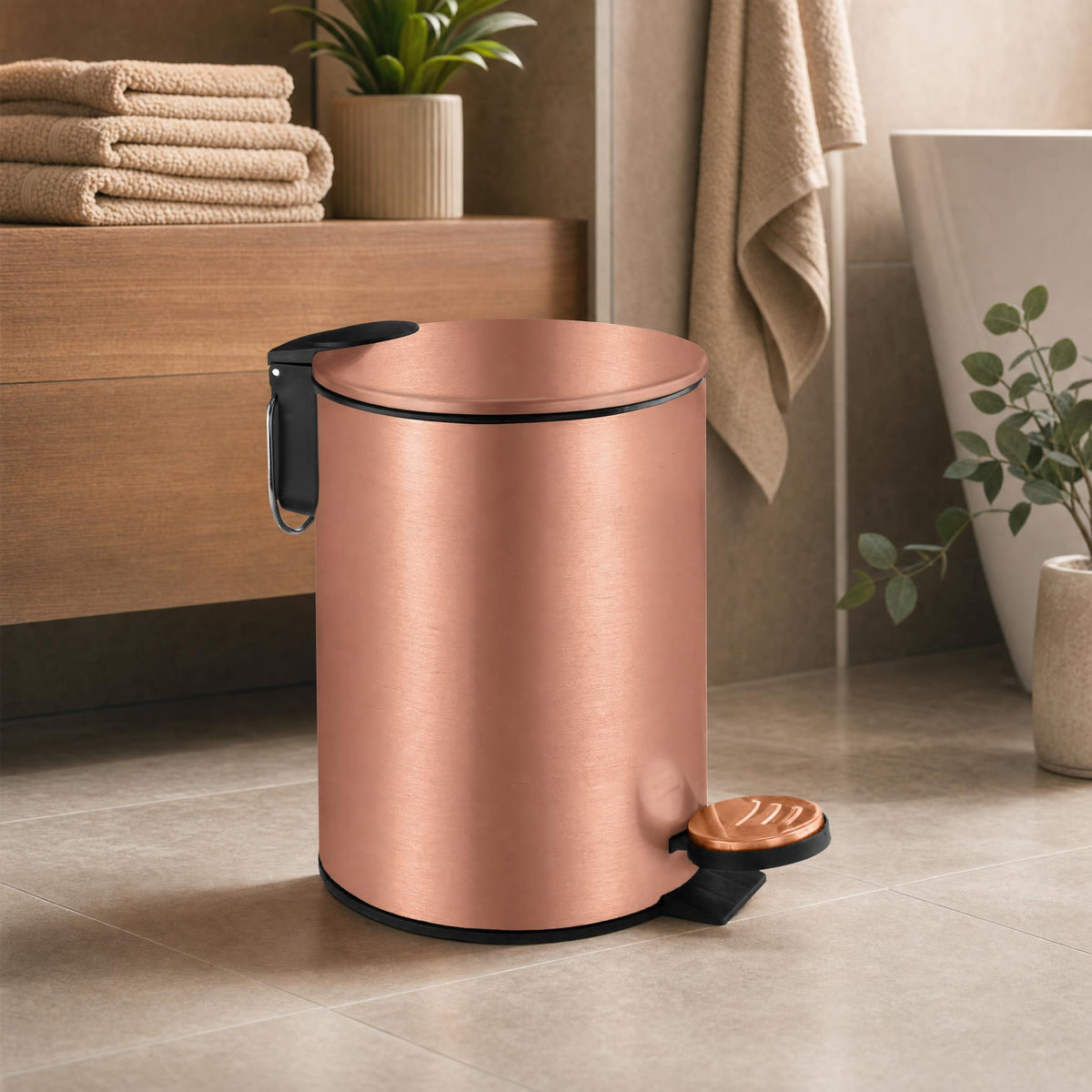 Roségoldfarbener Treteimer im Badezimmer mit Handtüchern und Badewanne.