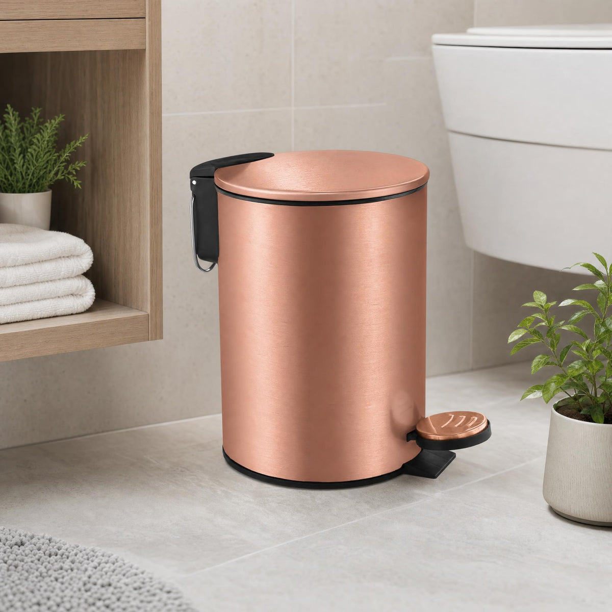 Roségoldfarbener Treteimer im modernen Bad neben Regal und Toilette.