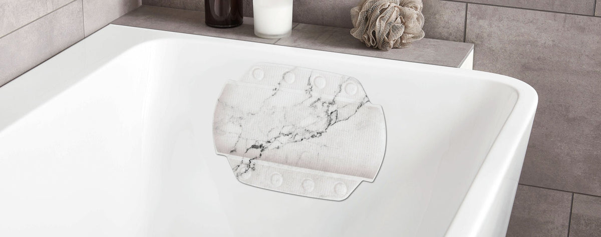 Weiße Badewanne mit Marmor-Rutschmatte, Seifenspender und Badeschwamm