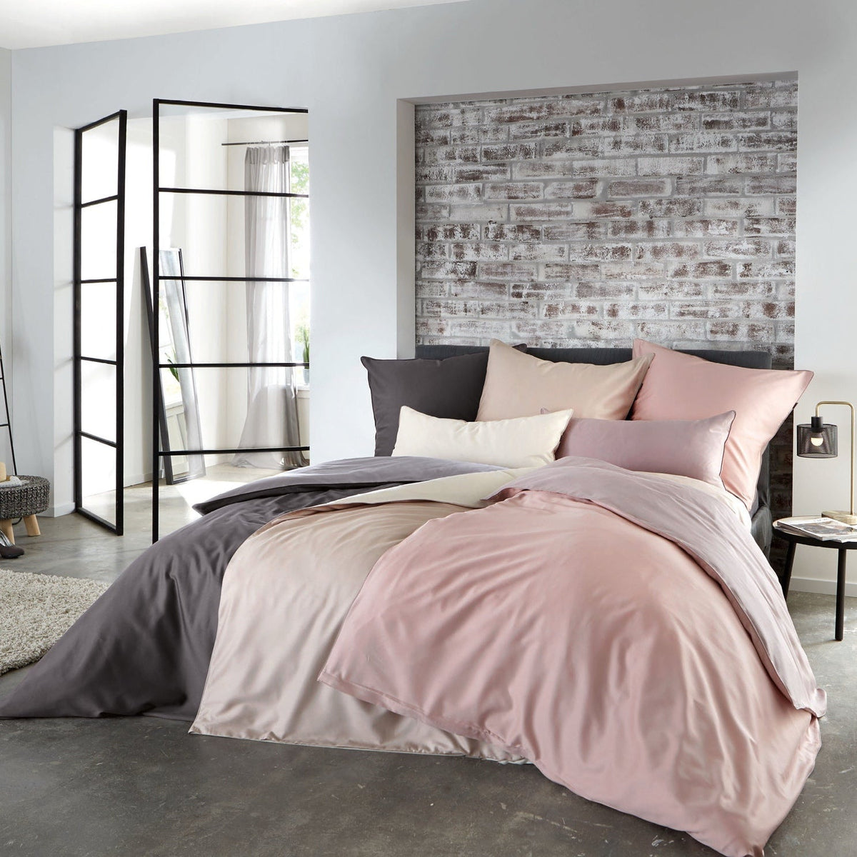 Modernes Boxspringbett mit roséfarbener Satin-Bettwäsche und Kissen