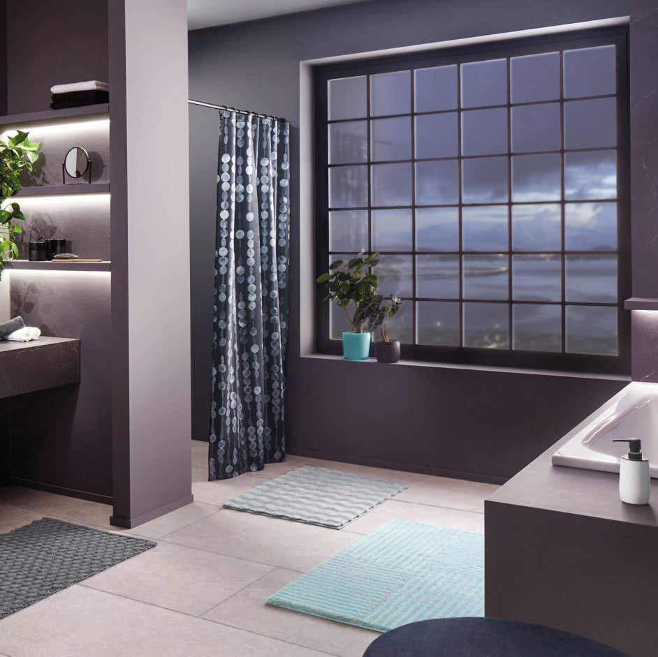 Modernes Badezimmer mit großer Fensterfront, Duschvorhang und Badematten