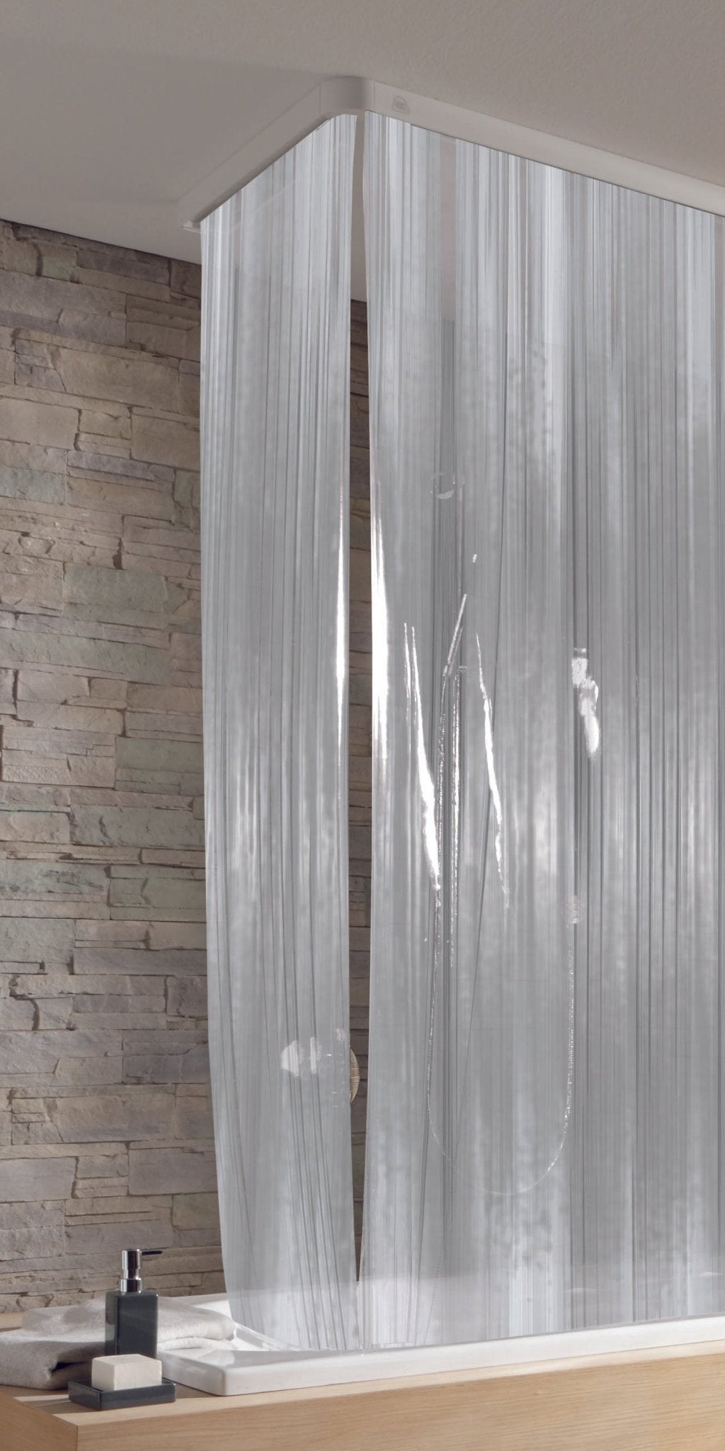 Transparenter Duschvorhang mit Streifen vor Badewanne und Steinwand